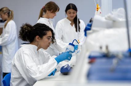 A group of women in lab coats working in a laboratory setting.