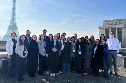 A group of people standing together with the Eiffel Tower in the background.