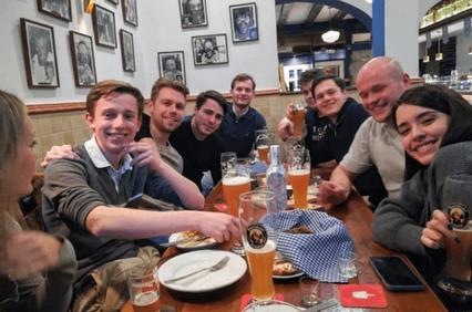A group of friends enjoying a meal together at a pub with drinks on the table.