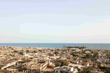 Aerial view of a coastal town with numerous buildings and distant views of the ocean.