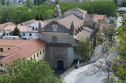 An aerial view of a historic building surrounded by greenery and other structures.