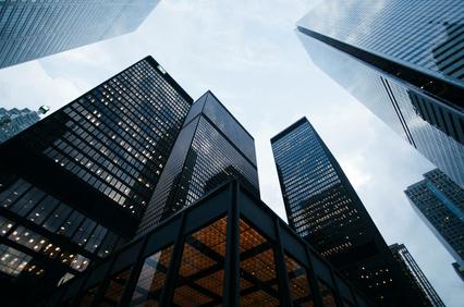 A view looking up at tall skyscrapers under a cloudy sky.