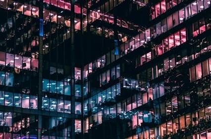 A modern building facade illuminated in vibrant colors at night.