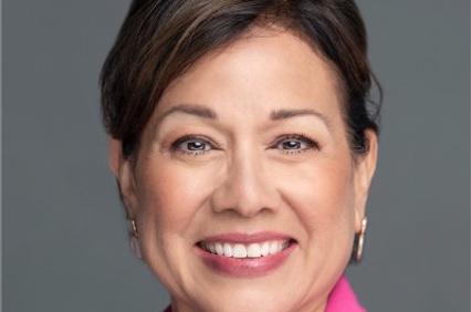 A smiling woman wearing a pink blazer.