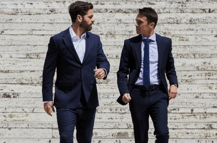 Two men in suits walking and conversing on stairs.