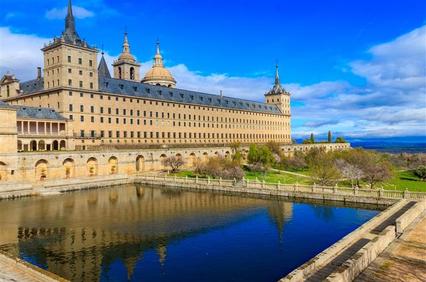 A stunning view of a historical monastery by a serene water body under a clear blue sky.