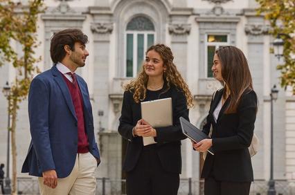 Three professionals engaged in conversation outdoors in a city setting.