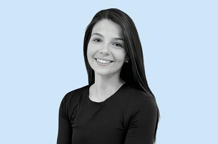 A portrait of a smiling young woman with long hair, wearing a black top against a blue background.