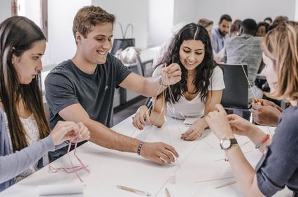 A group of young people is engaged in a hands-on activity involving string and crafting materials.