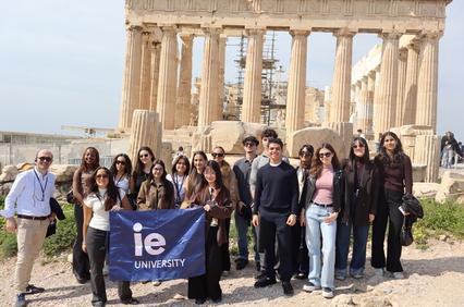 A group of students proudly holding a university banner in front of an ancient temple.