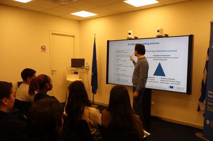 A presenter explaining the EU decision-making process to an audience in a meeting room.