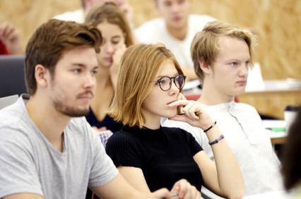 A group of students attentively listening in a classroom.