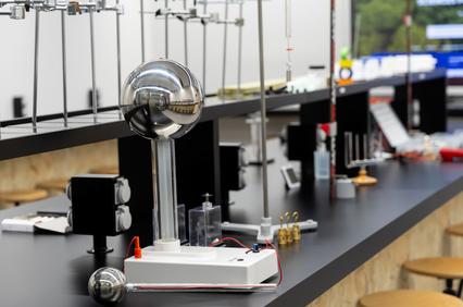 A laboratory setup featuring a spherical electrode and various glass apparatuses on a counter.