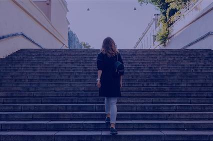 A person walking up a set of stairs in a subdued light.