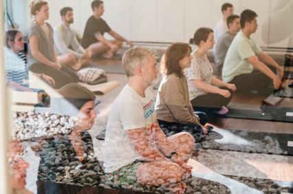 A group of people are sitting in a meditation pose during a yoga class.