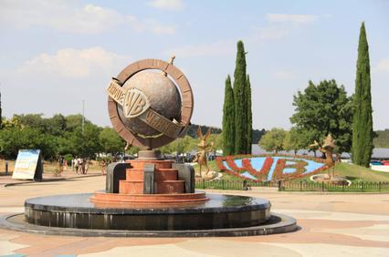 A globe monument with the WB logo surrounded by greenery and decorative elements.