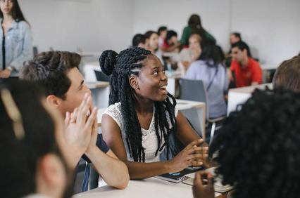 A diverse group of students engaged in discussion in a classroom setting.