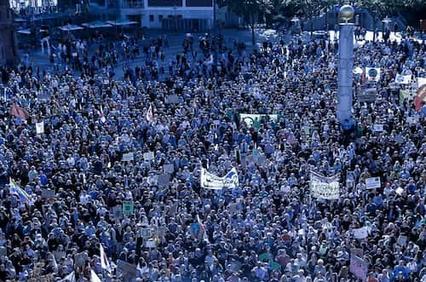 A large crowd of people gathered for a protest in an urban setting.