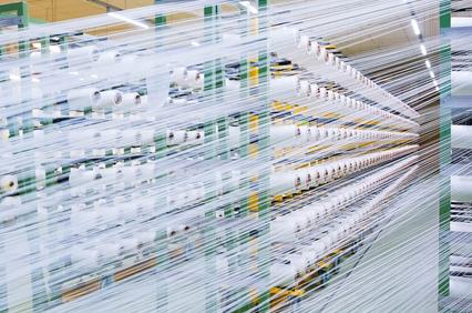 Long exposure shot of a busy textile factory with rows of fabric production machinery.