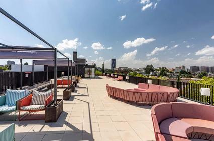 A modern rooftop terrace with stylish seating and a clear blue sky.