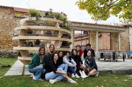 A group of women poses together in front of a unique spiral garden structure.