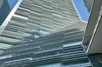 A modern glass skyscraper reaching towards the blue sky.
