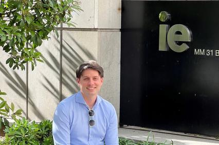 A man smiling in front of a building with the 'ie' logo.