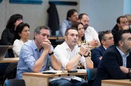 A group of attentive adults sitting in a conference room during a presentation.