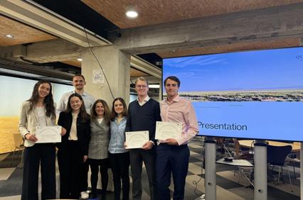 A group of people standing together holding certificates in a modern presentation space.