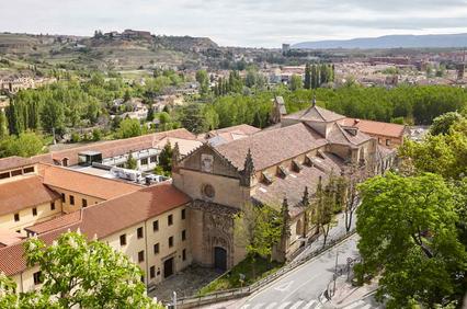 A scenic view of a historical building surrounded by greenery and hills.