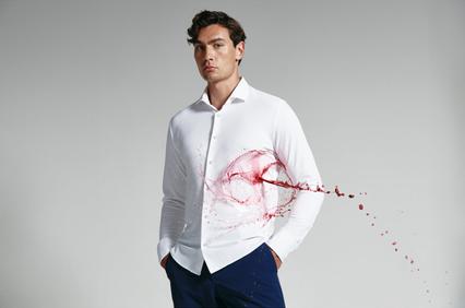 A man in a white shirt with a dynamic red splash design across it, posing on a grey background.