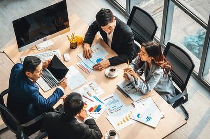 A group of professionals discussing data and charts in a modern office setting.