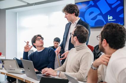 A group of students in a university classroom engaging in discussion with a teacher.