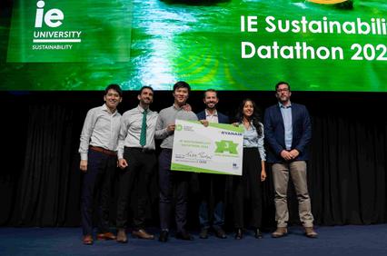 A group of six individuals stands on stage holding an award for the IE Sustainability Datathon 2022.