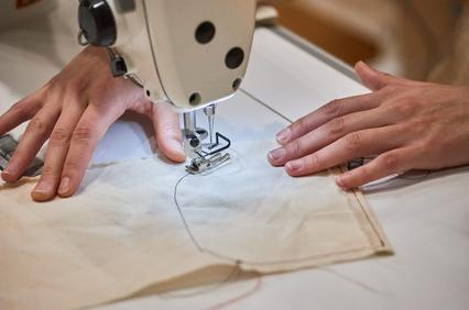 A person sewing with a sewing machine on a piece of fabric.