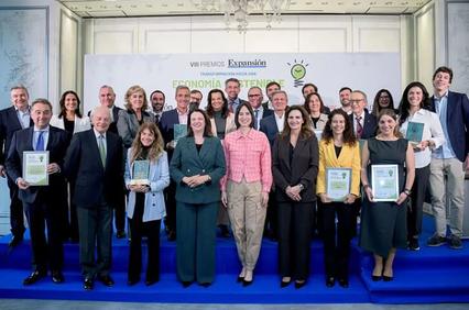 A group of men and women in formal attire posing with awards at an event.