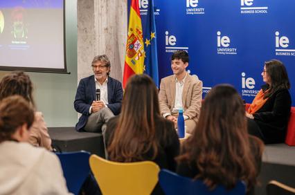 Four people participate in a panel discussion in front of an audience at a university event.