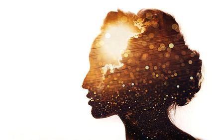 A silhouette of a woman filled with a vibrant sunset and bokeh lights.