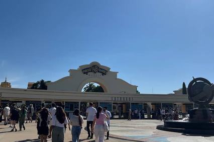 People walking towards a modern building entrance under a clear blue sky.