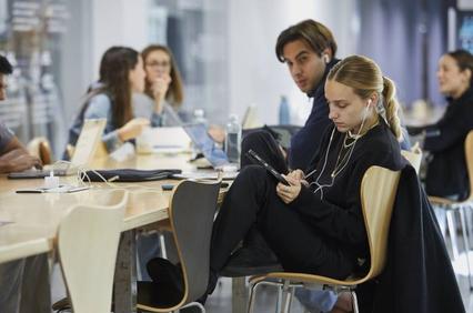 Young adults are working and using electronic devices at a modern office table.