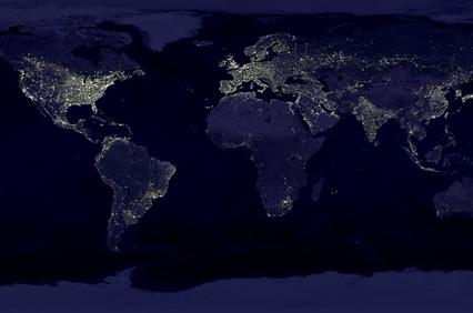 A satellite image of Earth at night showing the illuminated areas of human habitation.