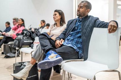 People sitting in a waiting area, looking in different directions with expressions of anticipation.