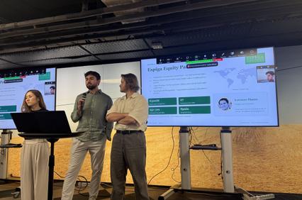 A group presentation in an office setting with a speaker and two audience members.