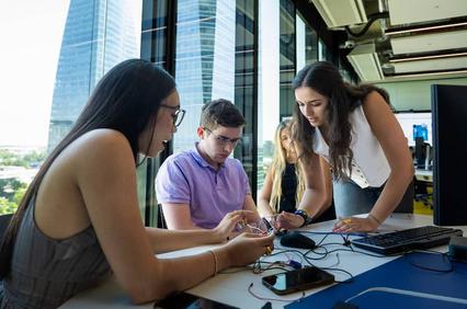 A group of young people collaborating on a project with technology in a modern office environment.