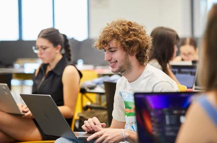 A group of students working on laptops in a collaborative study environment.