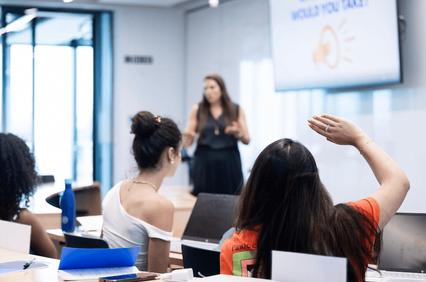 A group of people seated in a classroom with a speaker presenting in front of them.