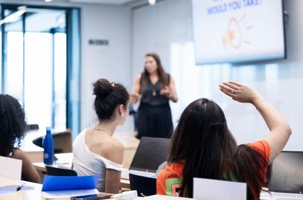A group of students in a classroom actively engaging with a speaker.