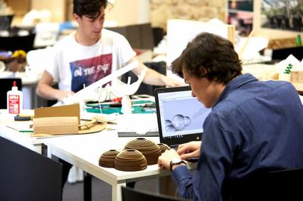 Two students working on architectural models in a studio.