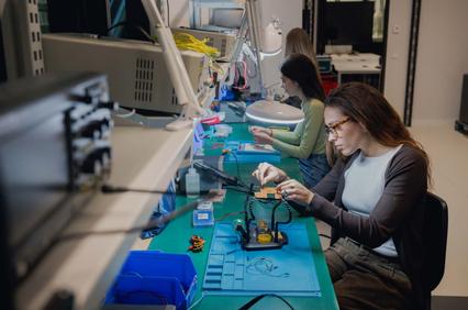 A group of people working on electronic components at a laboratory desk.