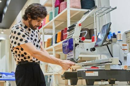 A man is operating a sewing machine in a colorful workshop.